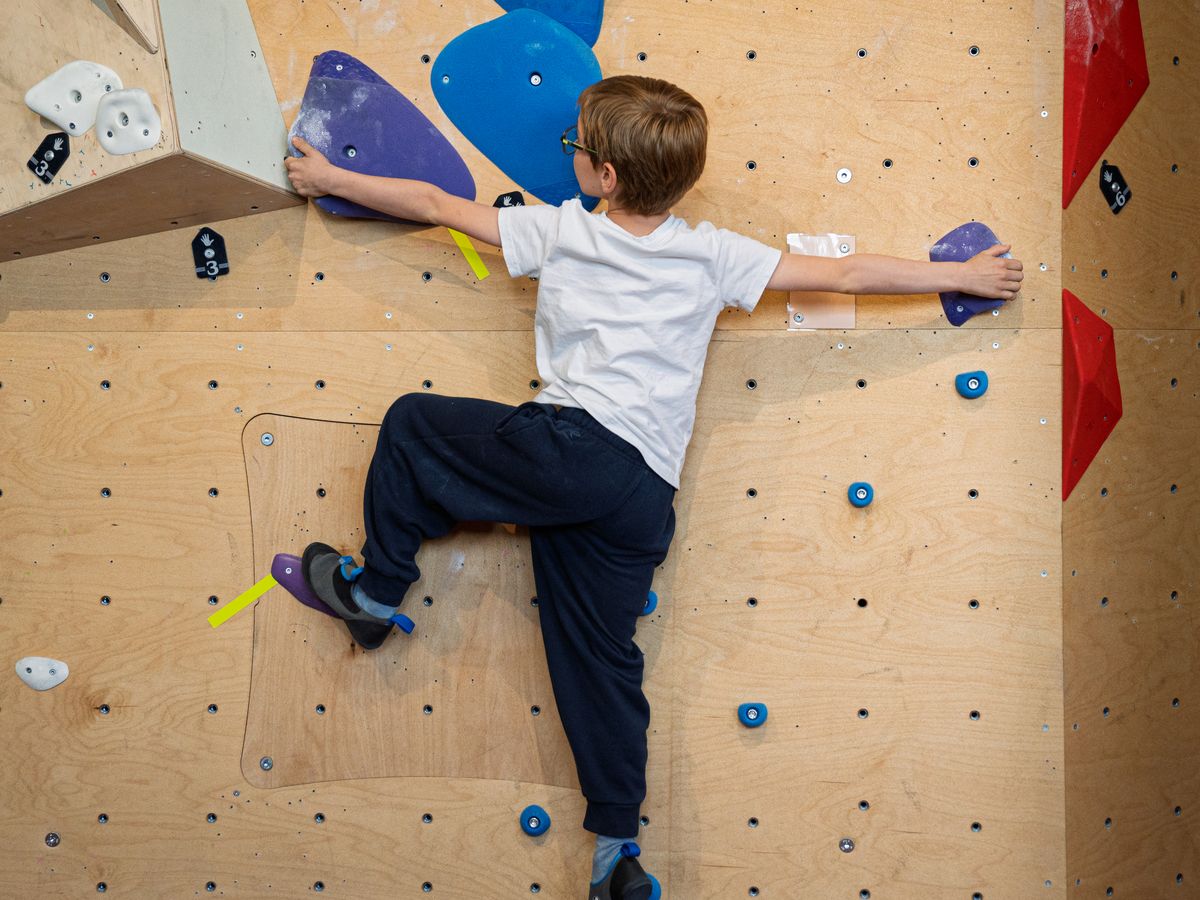 Un enfant grimpe sur les murs d'escalade ESCAPAD, au même étage que le Café Central